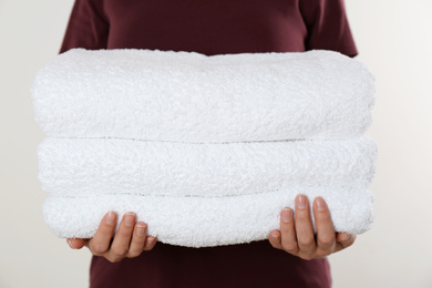 Woman holding fresh towels on light background, closeup