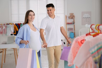 Photo of Happy pregnant woman and her husband with shopping bags in store