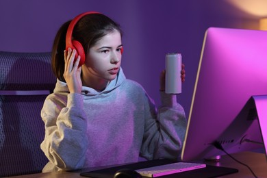 Photo of Girl with energy drink playing computer game at home