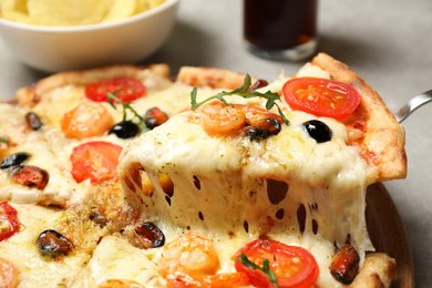 Photo of Taking slice of cheese pizza with seafood at table, closeup