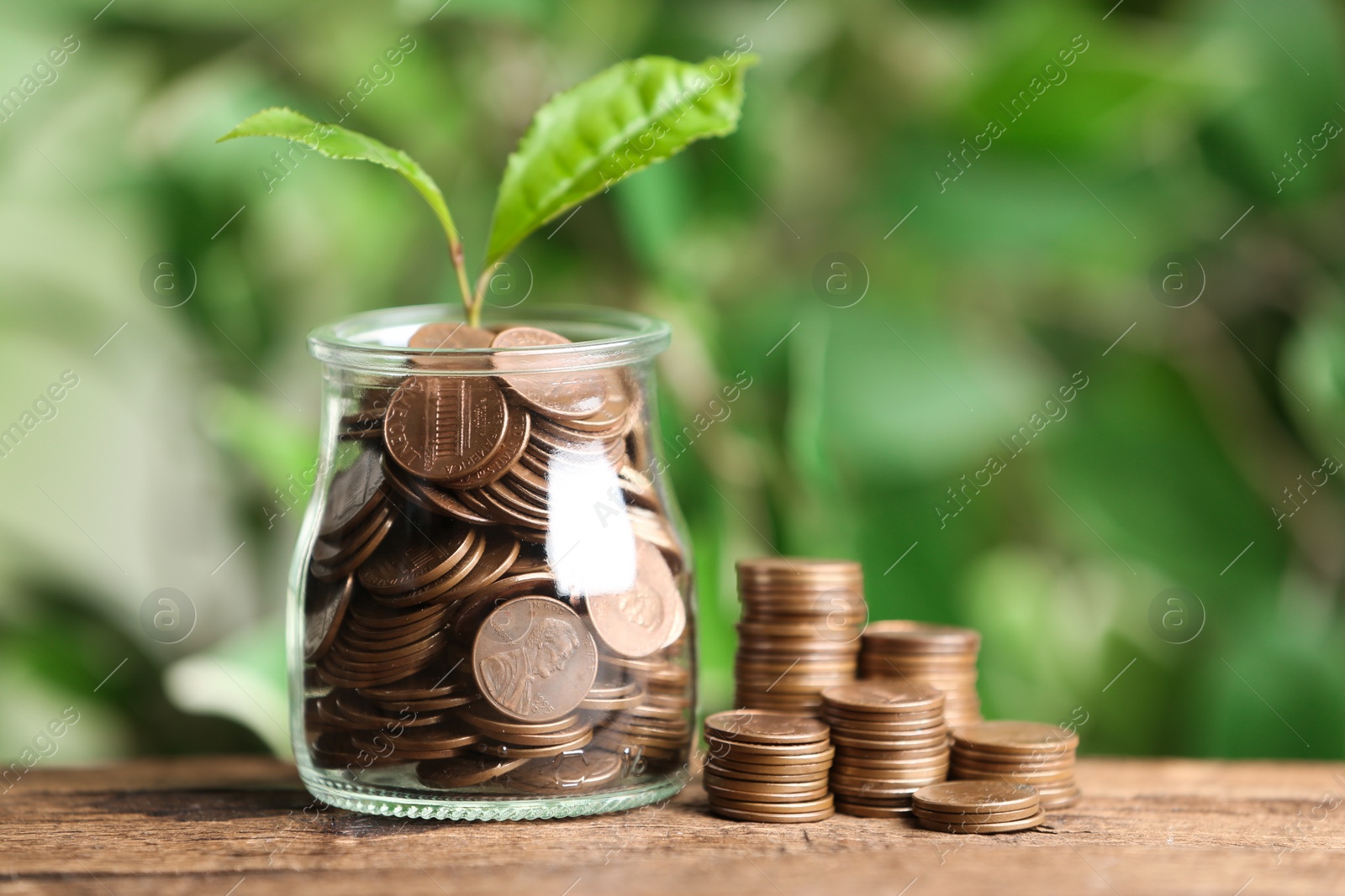 Photo of Money and sprout on wooden table against green blurred background