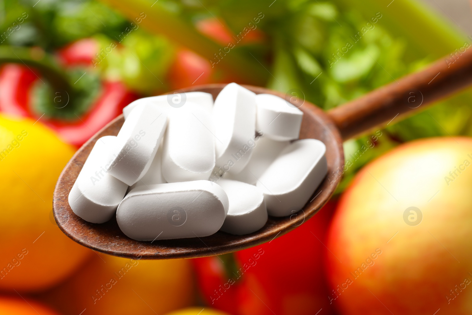 Photo of Dietary supplements. Spoon with pills over food products, closeup