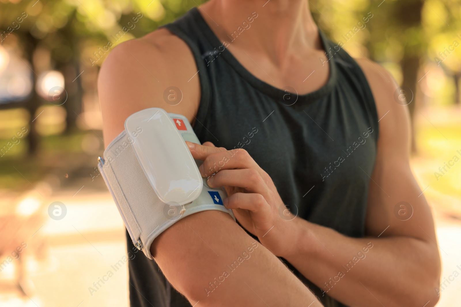 Photo of Man checking blood pressure with modern monitor after training on sunny day, closeup