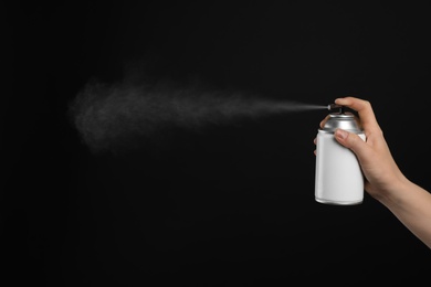 Woman spraying air freshener on black background, closeup