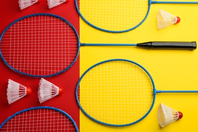 Badminton rackets and shuttlecocks on color background, flat lay