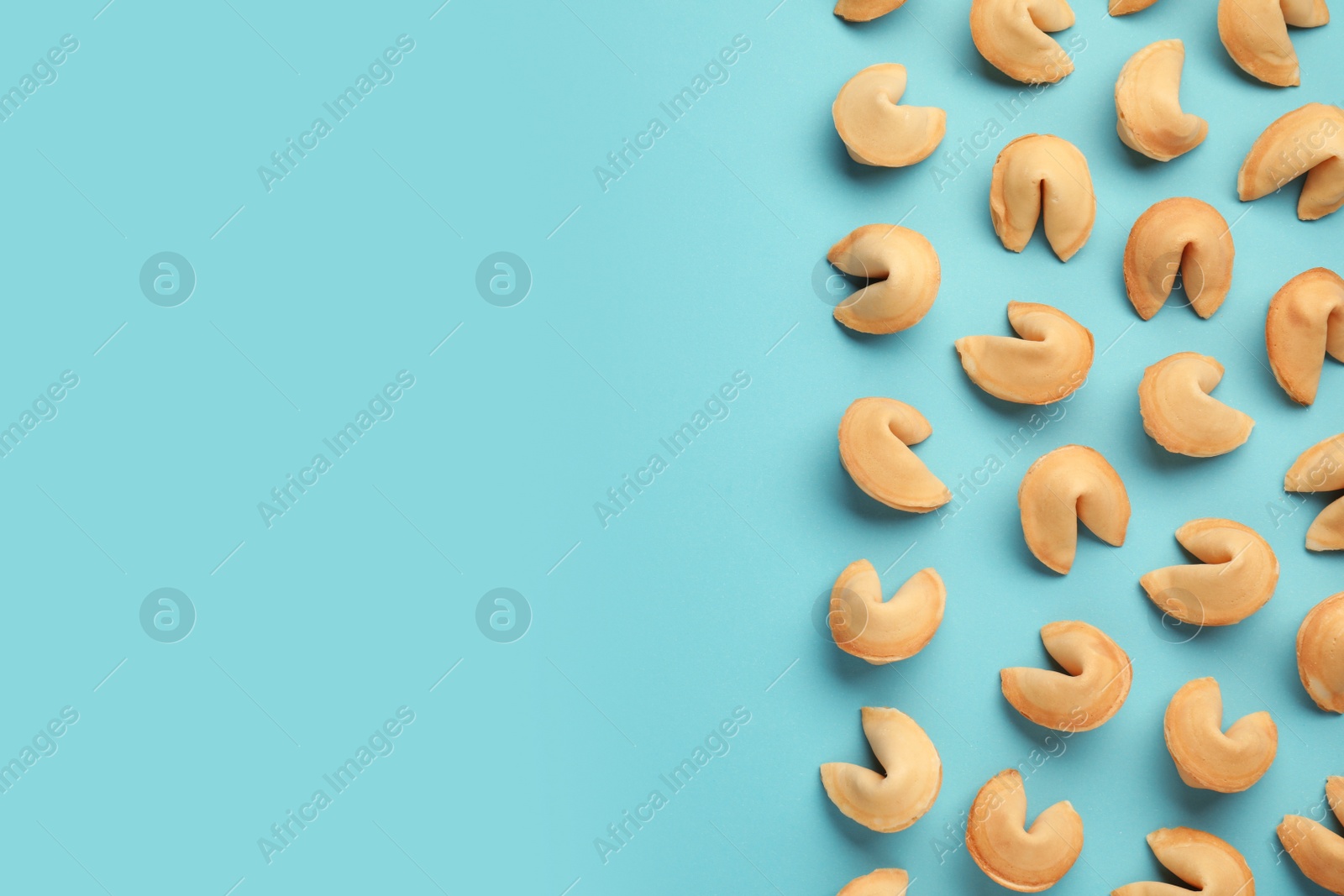 Photo of Tasty fortune cookies with predictions on light blue background, flat lay. Space for text