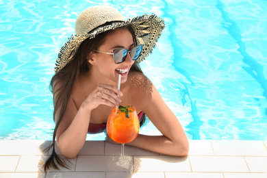 Photo of Woman with glassrefreshing drink in swimming pool