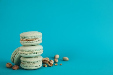 Delicious macarons and pistachios on light blue background, space for text