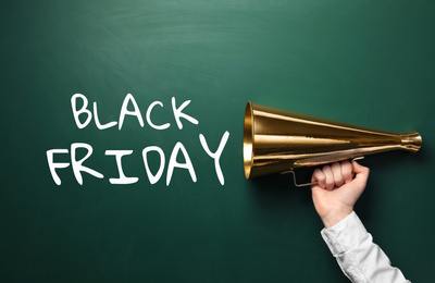 Man holding megaphone and text BLACK FRIDAY on chalkboard, closeup