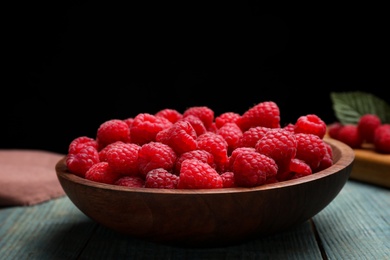 Photo of Delicious fresh ripe raspberries in plate on blue wooden table