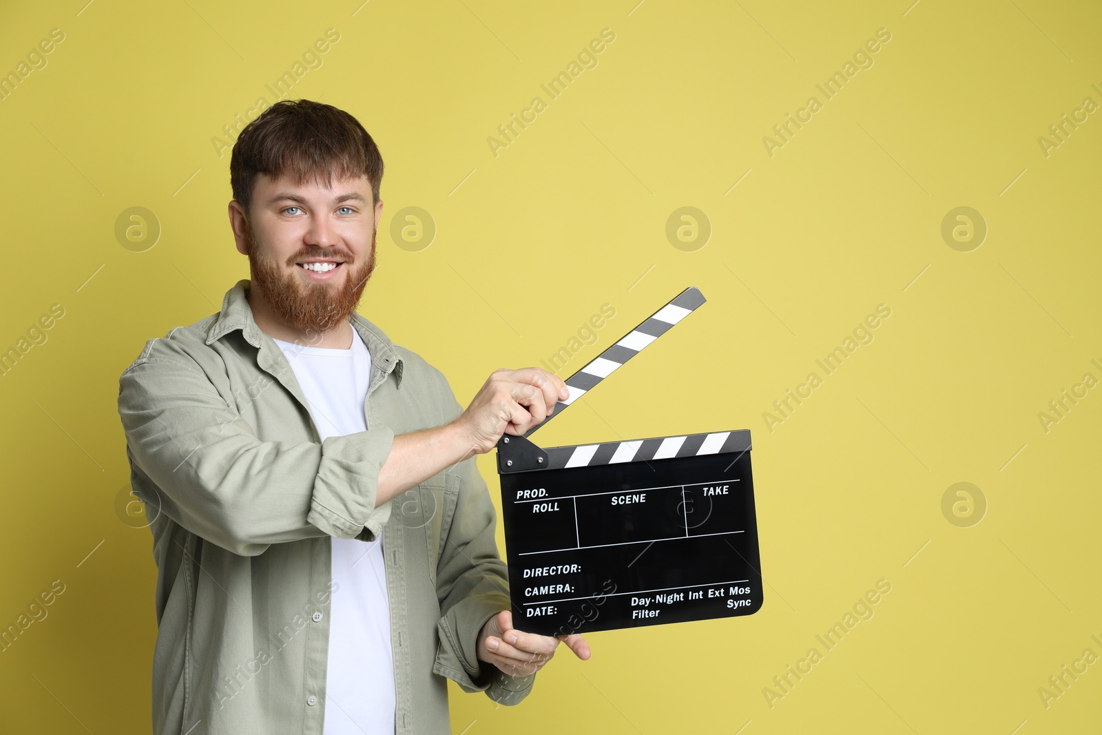 Photo of Making movie. Smiling man with clapperboard on yellow background. Space for text