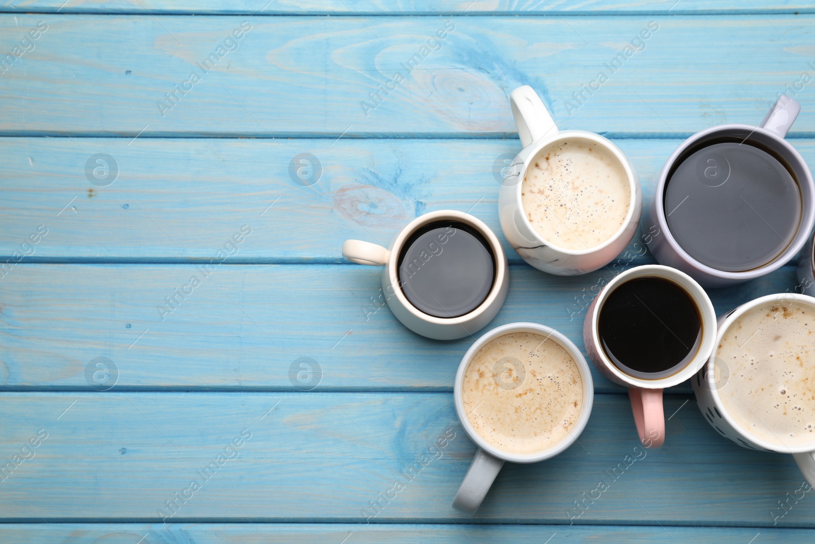 Photo of Many cups of different coffee drinks on light blue wooden table, flat lay. Space for text