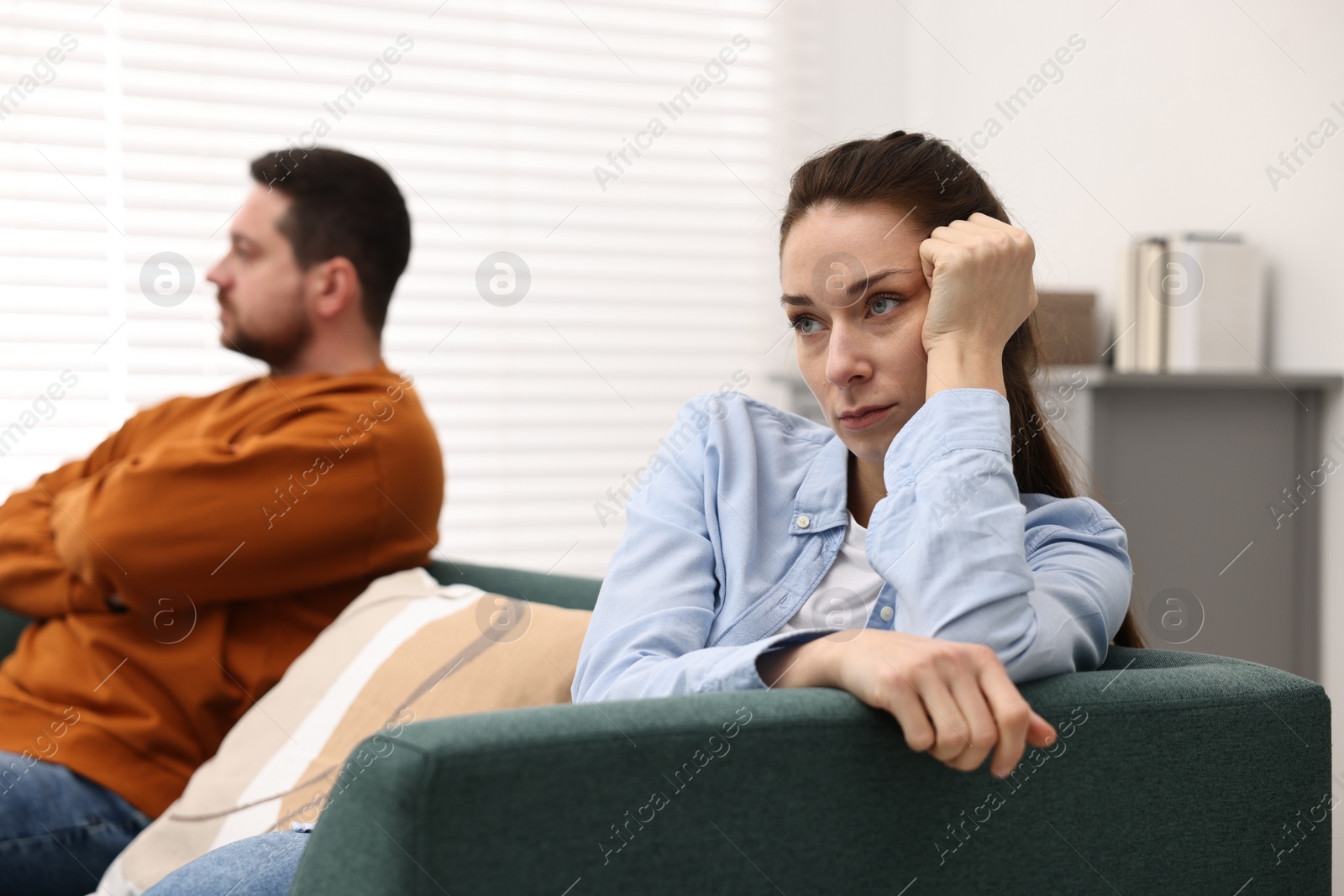 Photo of Offended couple ignoring each other after quarrel indoors, selective focus. Relationship problems