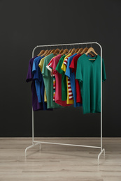 Photo of Rack with stylish clothes near black wall