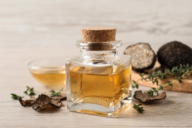 Photo of Fresh truffle oil and thyme on wooden table, closeup