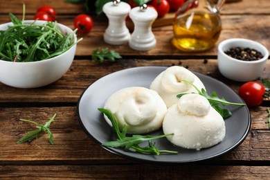 Photo of Delicious burrata cheese with arugula on wooden table