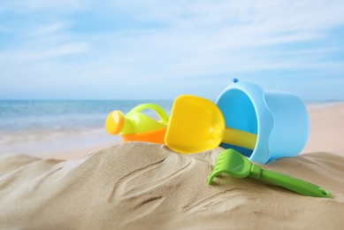 Image of Plastic toy set with shovel on sandy beach near sea 