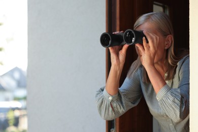 Concept of private life. Curious senior woman with binoculars spying on neighbours outdoors