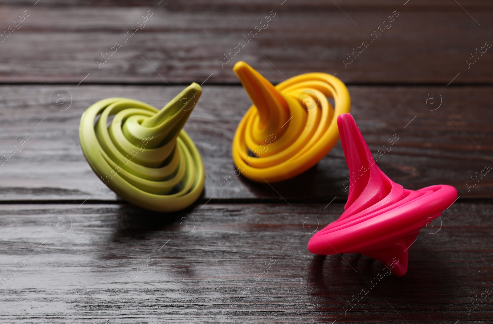 Photo of Bright spinning tops on wooden table, closeup