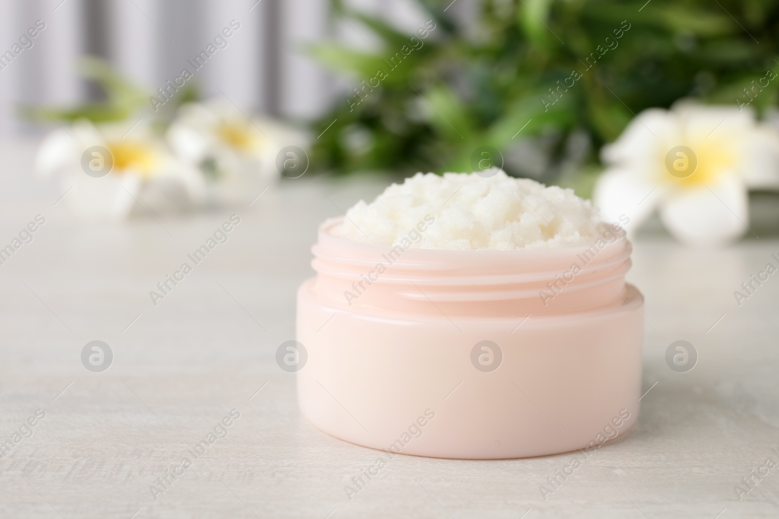 Photo of Jar of shea butter on table against blurred background. Space for text