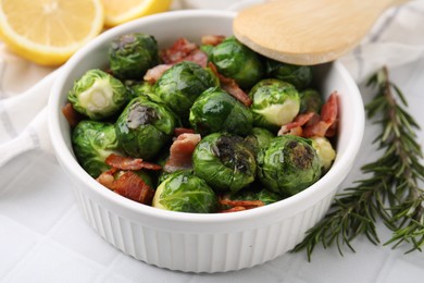 Photo of Delicious roasted Brussels sprouts, bacon and rosemary on table, closeup
