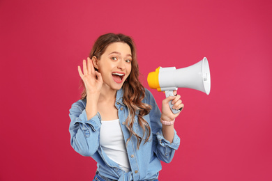 Young woman with megaphone on pink background