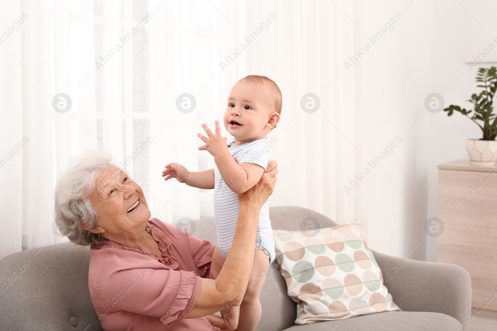 Photo of Happy grandmother with little baby at home