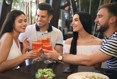 Photo of Friends with Aperol spritz cocktails resting together at restaurant