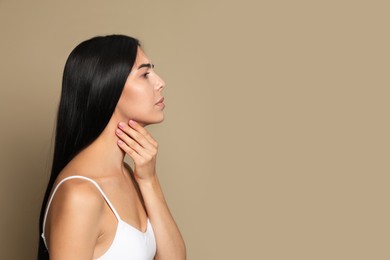 Photo of Young woman doing thyroid self examination on beige background. Space for text