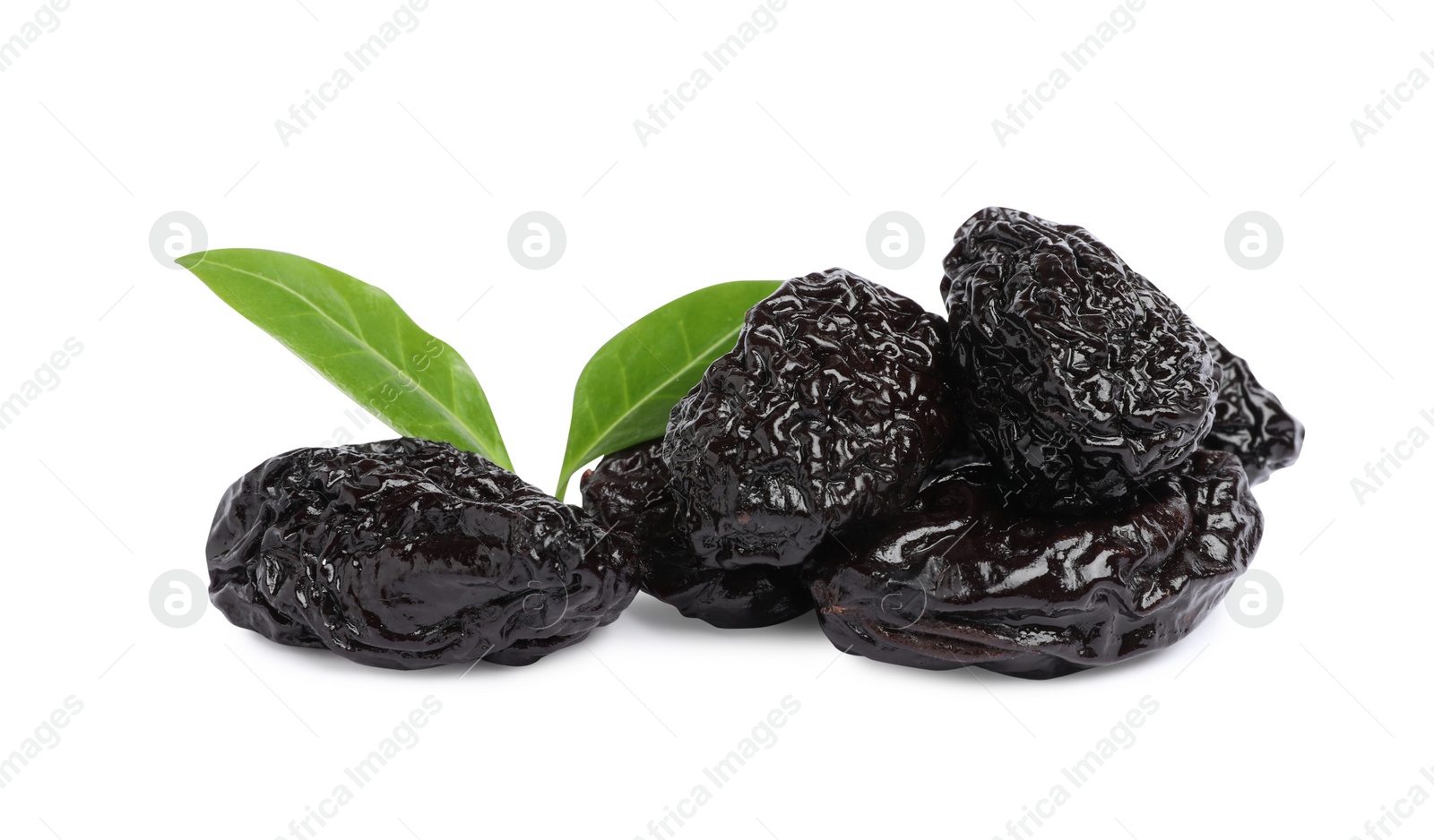 Photo of Heap of sweet dried prunes and green leaves on white background