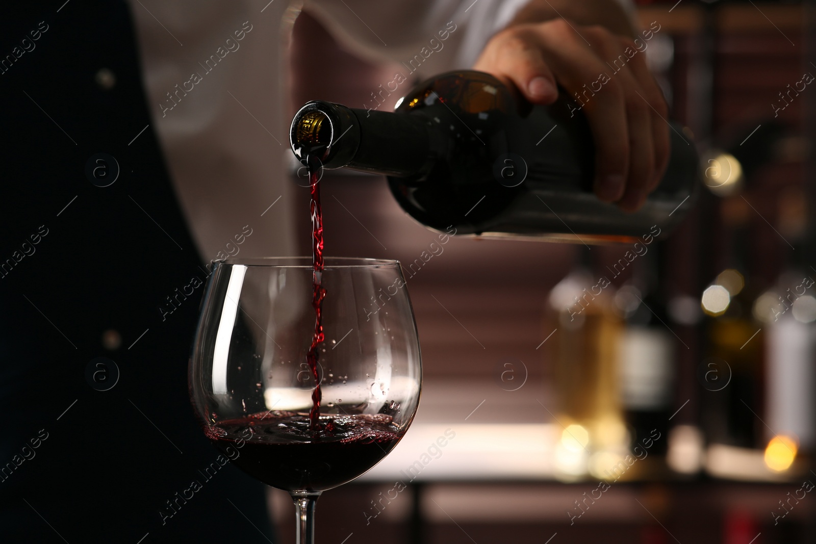 Photo of Bartender pouring red wine into glass indoors, closeup