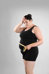 Photo of Fat woman with measuring tape on grey background. Weight loss