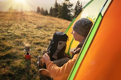 Photo of Man with cup of hot drink in camping tent outdoors