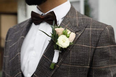 Photo of Groom in elegant suit with beautiful boutonniere outdoors, closeup. Preparing for wedding