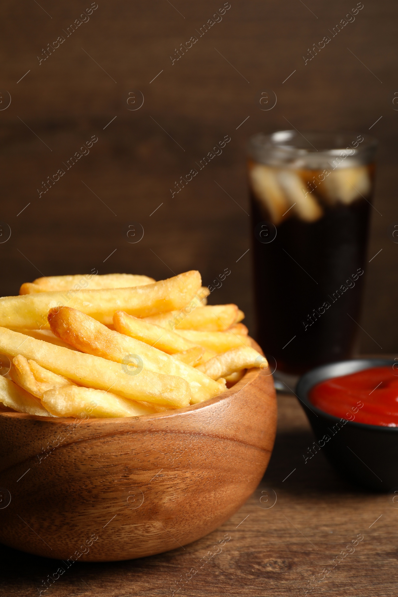 Photo of Delicious fresh french fries in bowl on wooden table, closeup