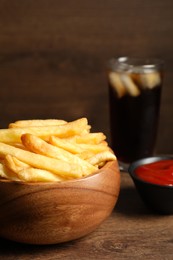 Delicious fresh french fries in bowl on wooden table, closeup