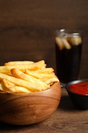 Photo of Delicious fresh french fries in bowl on wooden table, closeup