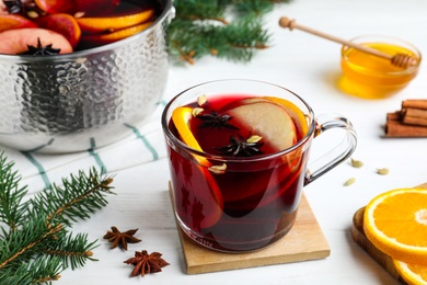 Delicious mulled wine and ingredients on white wooden table