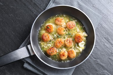 Delicious scallops with sauce in frying pan on dark gray textured table, top view