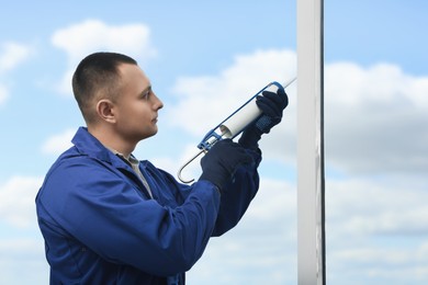 Photo of Construction worker sealing window with caulk indoors