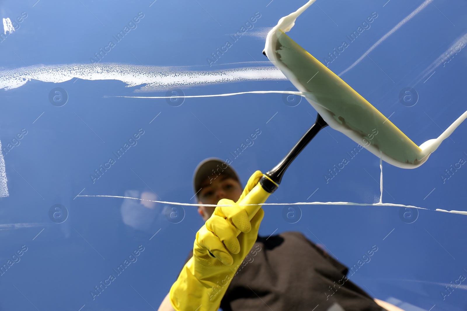 Photo of Woman cleaning glass with squeegee on sunny day