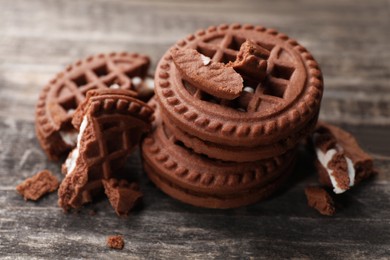 Photo of Tasty chocolate sandwich cookies with cream on wooden table, closeup