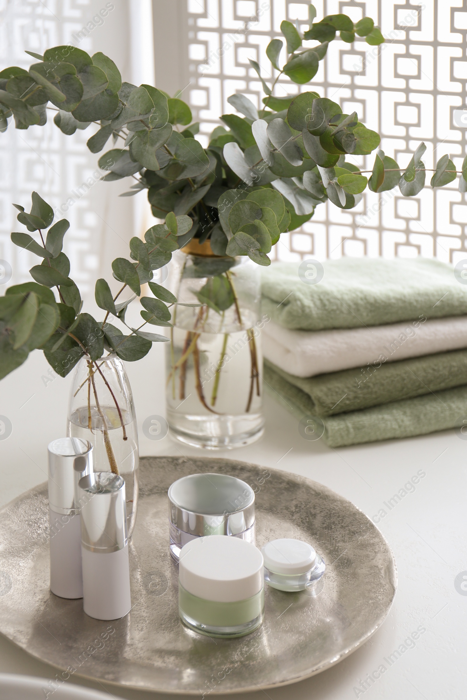 Photo of Fresh eucalyptus branches and cosmetic products on countertop in bathroom