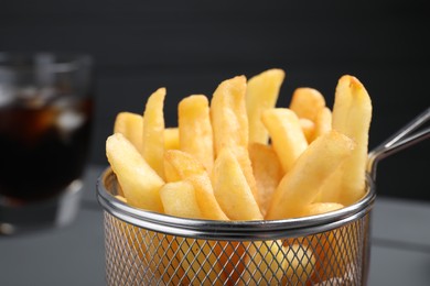 Metal basket with tasty French fries, closeup