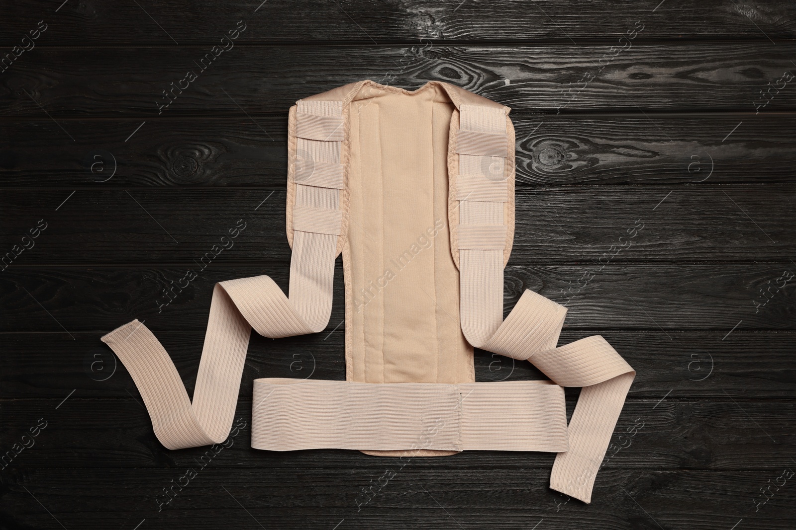 Photo of Beige posture corrector on black wooden table, top view