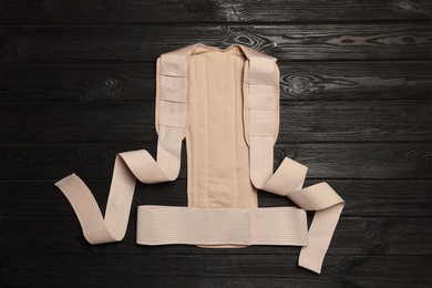 Beige posture corrector on black wooden table, top view