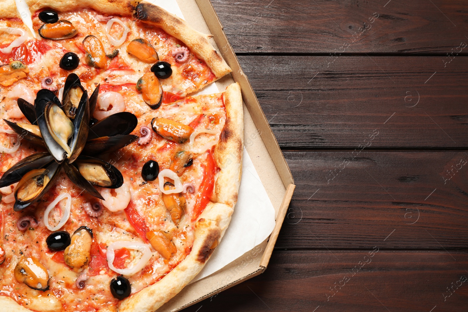 Photo of Tasty pizza with seafood on wooden table, top view. Space for text