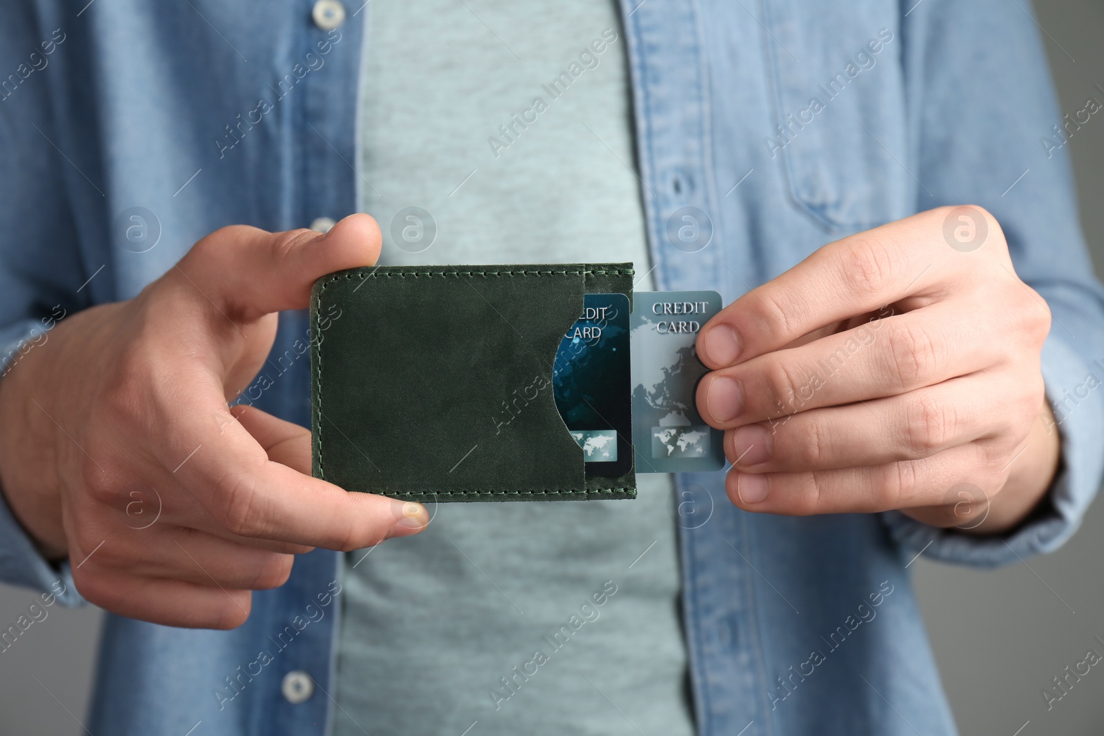 Photo of Man holding leather card holder with credit cards on grey background, closeup