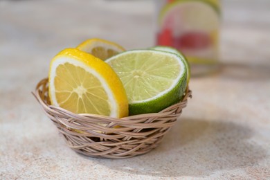 Photo of Basket with fresh citrus fruits on beige table, closeup