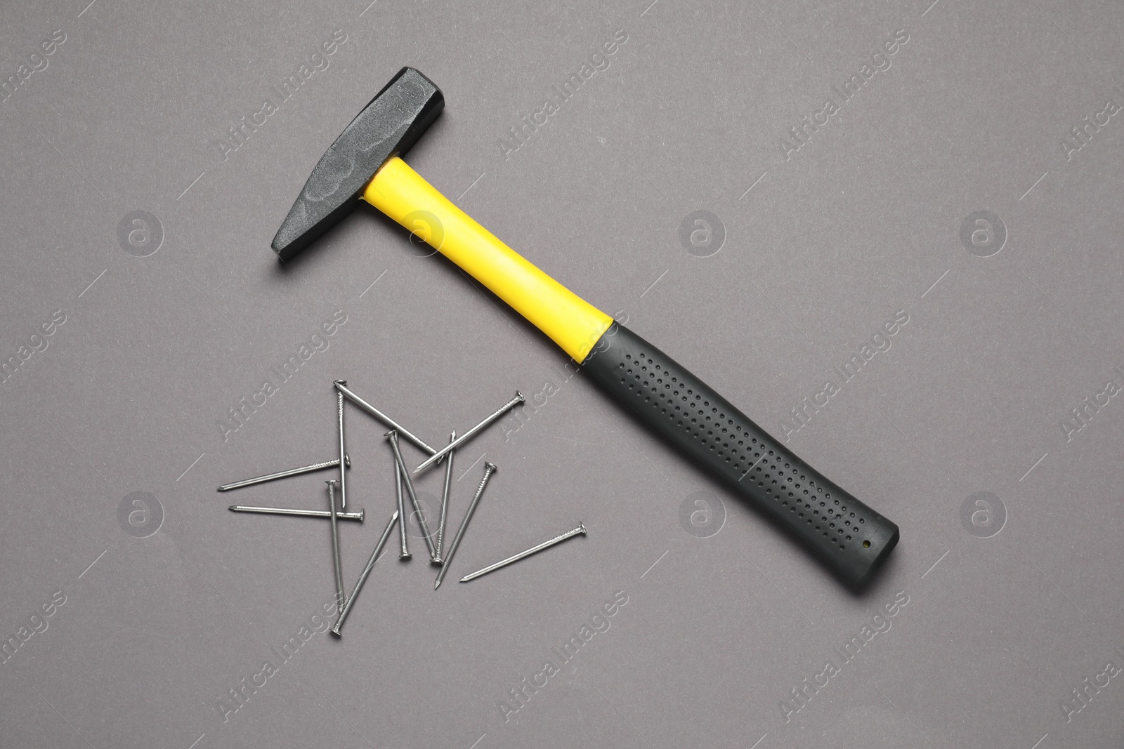 Photo of Hammer and metal nails on grey background, top view